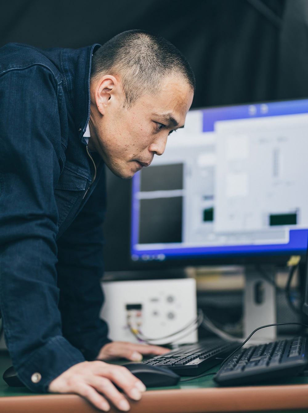 難しい顔でPCを覗き込んでいるシグマLISカンパニーの社員